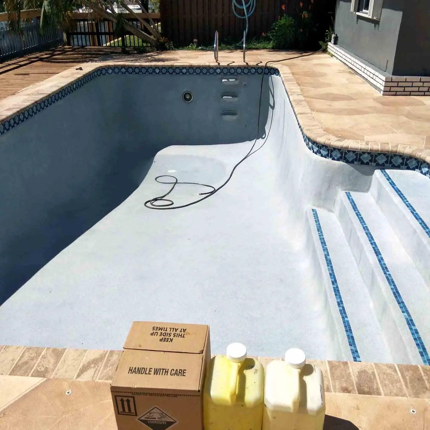 Empty in-ground pool under renovation with maintenance equipment and supplies at poolside - Aqua King Pool Services, Fort Lauderdale, FL