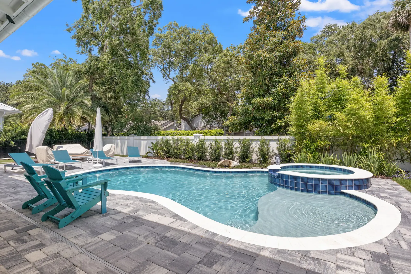Sparkling clean resort-style pool and spa with lounge chairs and landscaping in sunny backyard - Coastal Luxury Outdoors, Jacksonville, FL