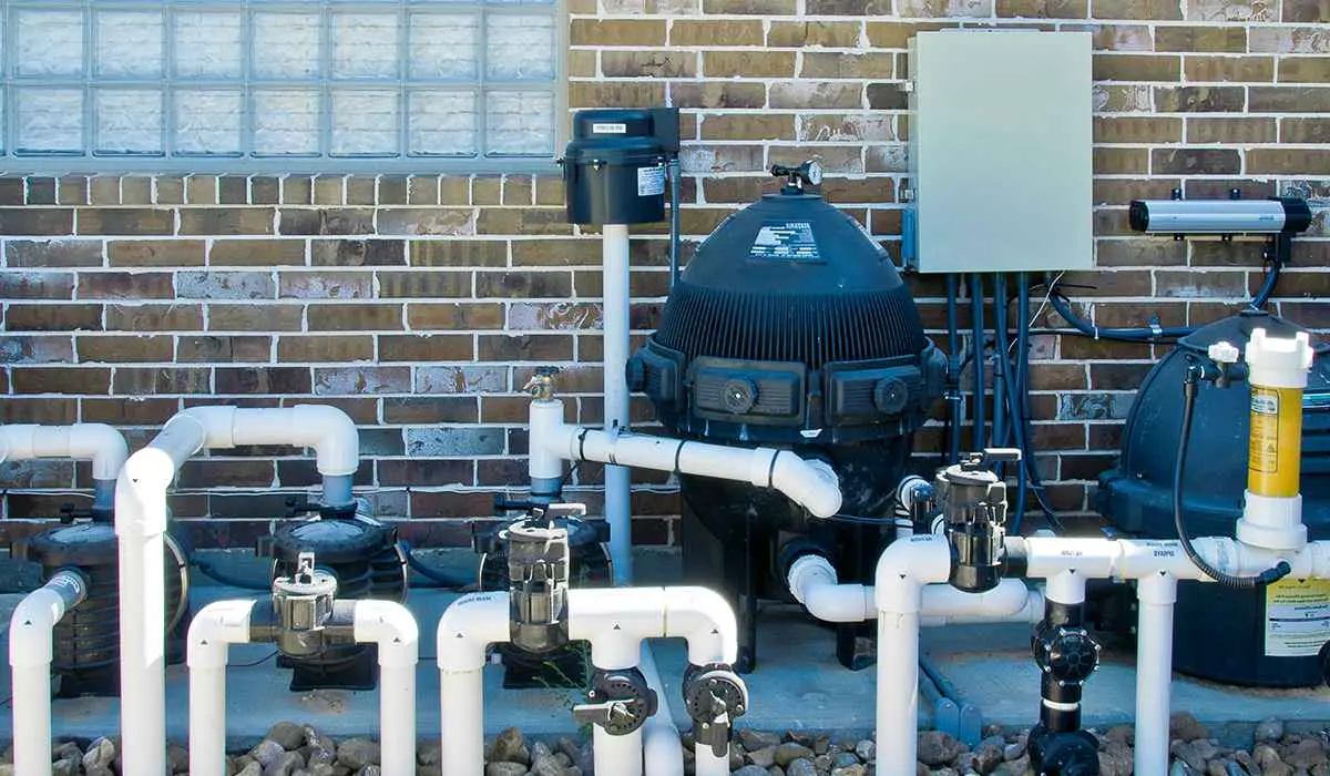 Pool equipment installation with pump, filter and piping on gravel against brick wall - Blue Science Pool Service, Tampa, FL