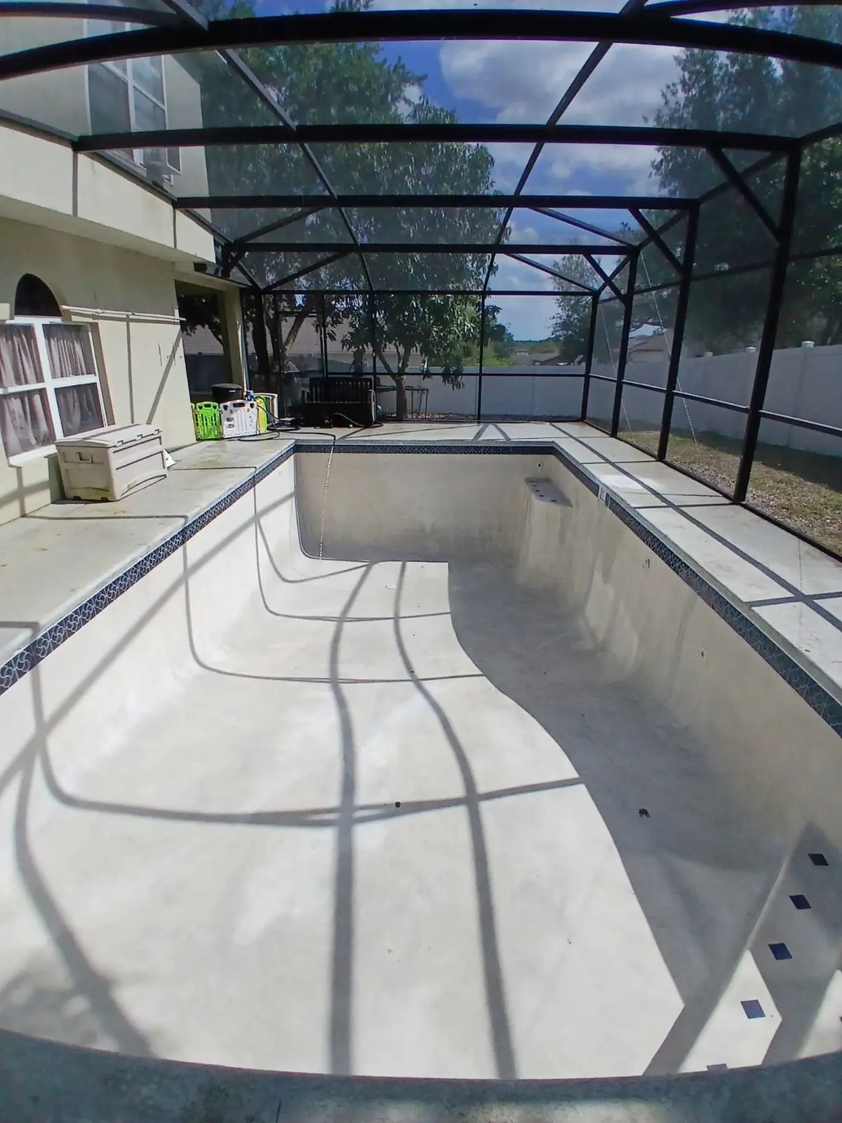 Empty in-ground pool interior under construction or repair with a screened enclosure - Leak Wizard, Tampa, FL