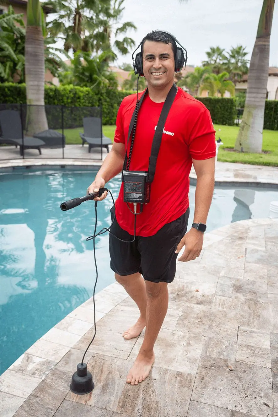 Man in red company shirt at pool holding microphone and wearing headphones - RED RHINO, The Pool Leak Experts, Tampa, FL