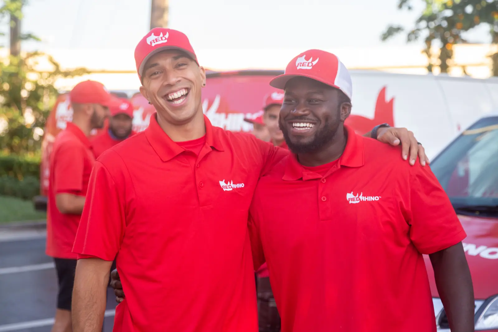RED RHINO pool service team members in red branded uniforms smiling outdoors with company trucks - RED RHINO, The Pool Leak Experts, Tampa, FL