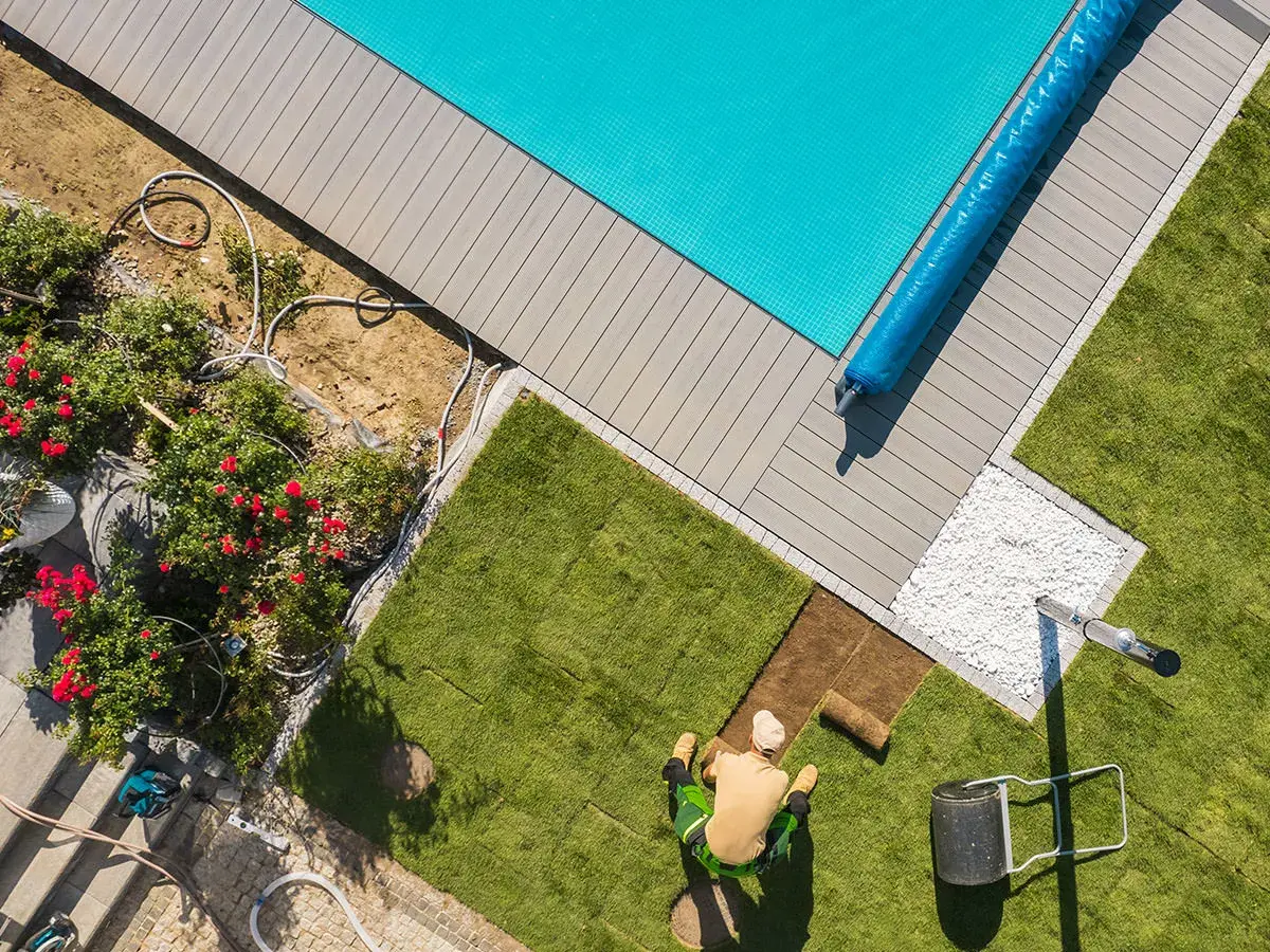 Aerial view of technician working on pool deck next to a sparkling clean pool with blue cover - Aaron's Leak Detection, Winter Springs, FL