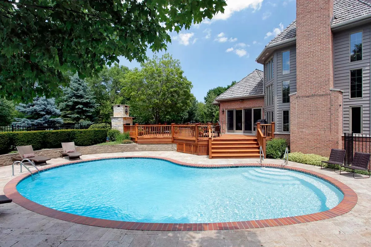 Sparkling clean backyard pool with brick deck, wood deck, and brick home - Aaron's Leak Detection, Winter Springs, FL
