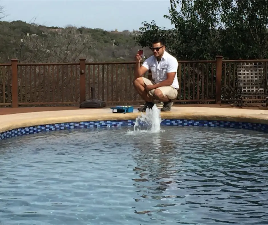 Technician in white uniform testing pool water at a residential spa - Hill Country Pools, Austin, TX