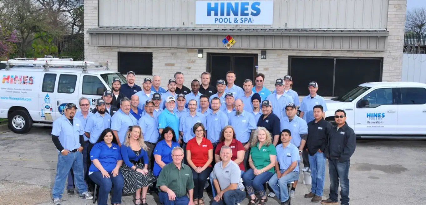 Hines Pool & Spa team members in branded uniforms standing in front of company vehicles and building - Hines Pool & Spa, Austin, TX