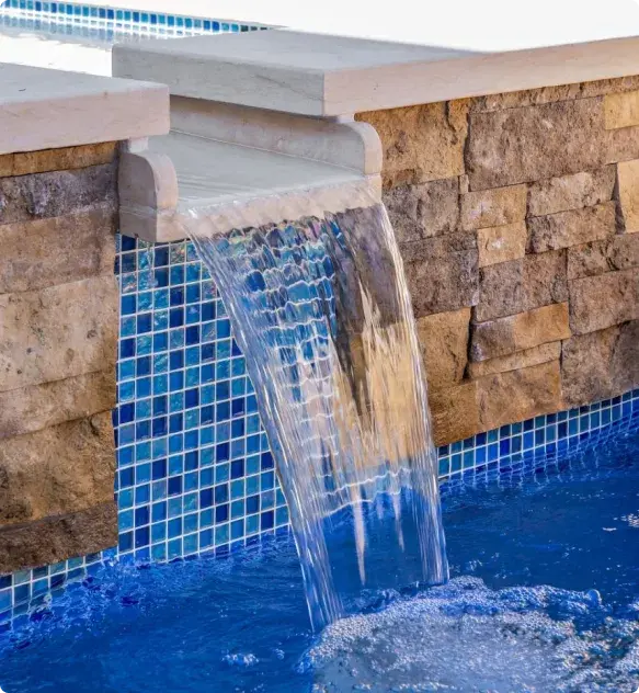 Clear blue pool with stone waterfall feature and blue tile work - Hines Pool & Spa, Austin, TX