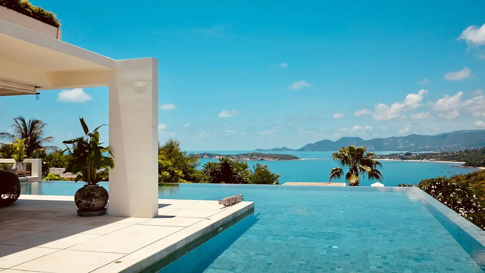 Luxury infinity pool overlooking turquoise ocean and mountains with palm trees and modern architecture - Awesome Pool Service, Corpus Christi, TX