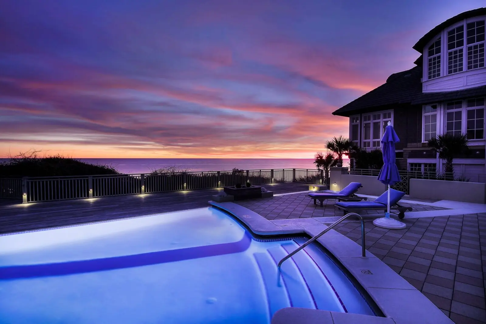 Illuminated swimming pool at dusk with spa, lounge chairs, and coastal home at sunset - Awesome Pool Service, Corpus Christi, TX