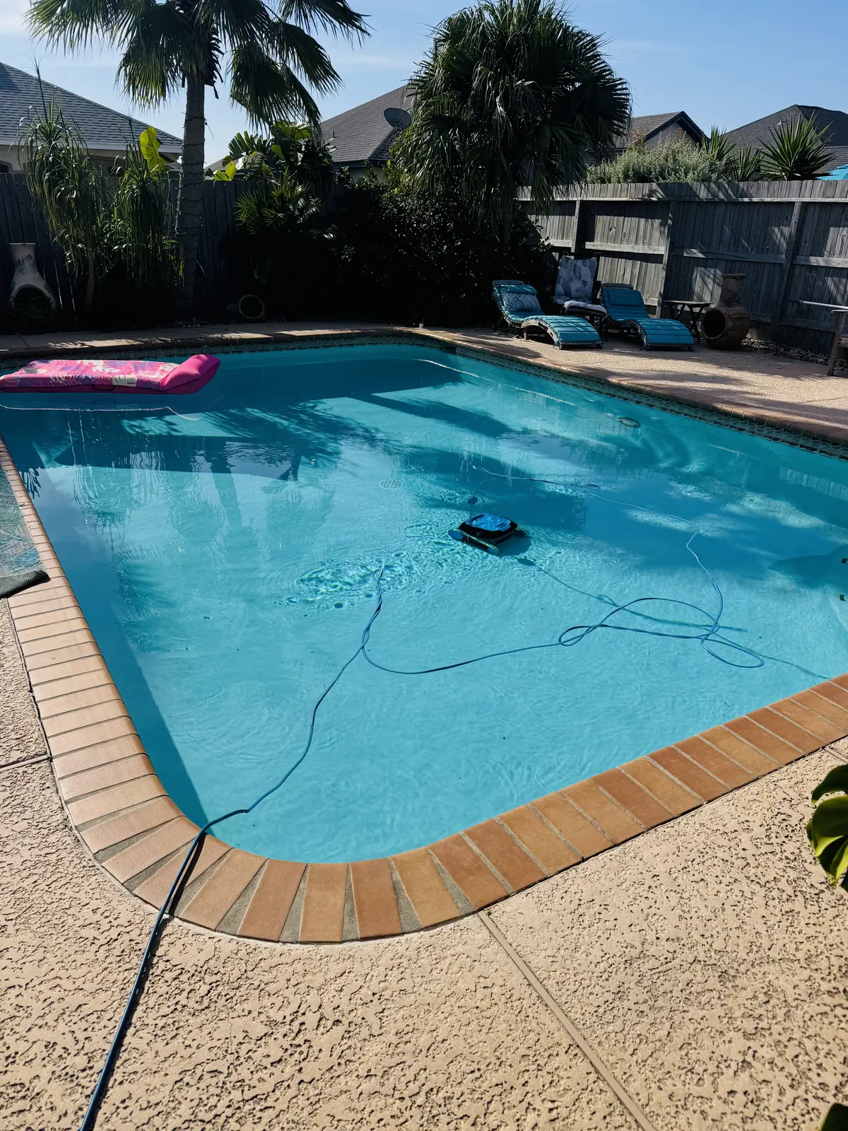 Backyard swimming pool with clear blue water, maintenance equipment visible, and lounge chairs on deck - Brad’s Pool Service, Corpus Christi, TX