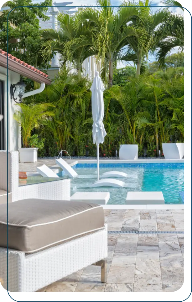Sparkling clean blue pool with white loungers, umbrella, and tropical palm landscaping - Brad’s Pool Service, Corpus Christi, TX
