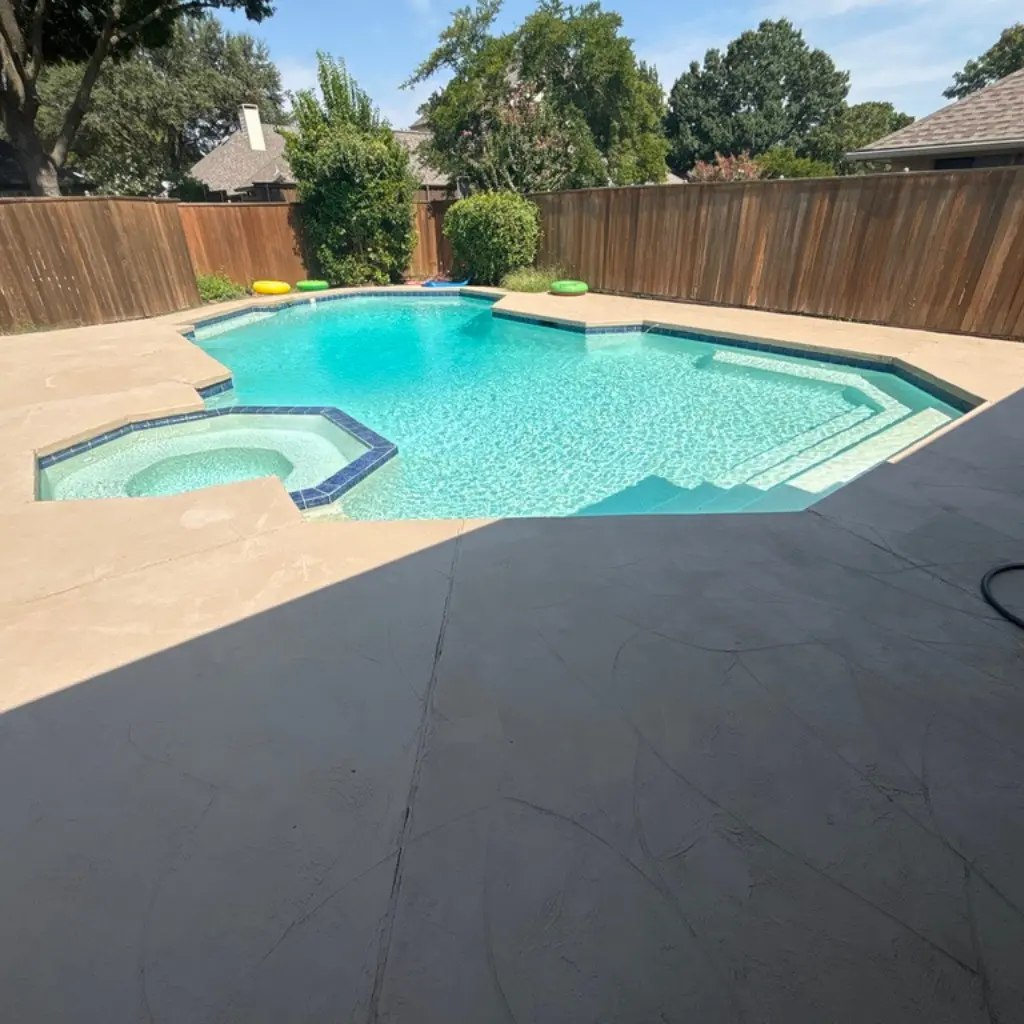 Sparkling clean swimming pool with attached spa and sun loungers in a fenced backyard - Refresh Pool Company, Dallas, TX