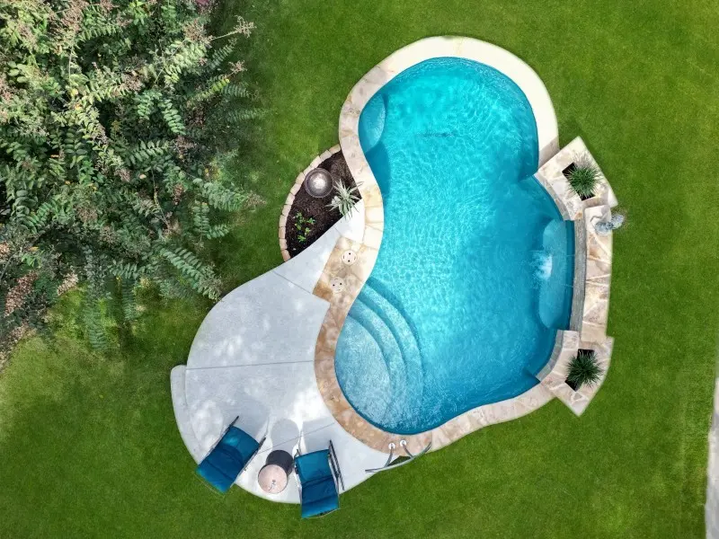 Aerial view of a sparkling blue kidney-shaped pool with white decking and manicured lawn - Gary Pools, San Antonio, TX